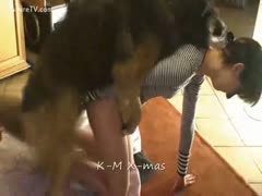 On the kitchen floor, a petite brunette wearing a black and white sweater walks her brown dog.